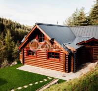 A wooden family house in Hnilčík surrounded by greenery and forest, with a sloped metal roof.