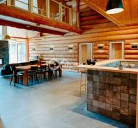 Interior of a family house with wooden walls, a dining table, and a light floor with a wooden decor.