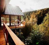 The family house in Hnilčík is surrounded by forest and has a wooden terrace with a view.