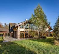 A family house in Veľká Lomnica is surrounded by greenery, with a stone facade and trees in the vicinity.