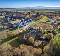 Aerial view of family houses in Veľká Lomnica with surrounding countryside and mountain backdrop.
