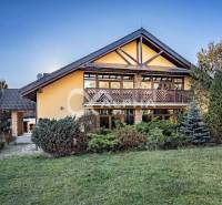 A family house in Veľká Lomnica with wooden elements, surrounded by greenery and a lawn.