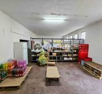 A warehouse in a building with food on shelves and drinks on pallets.