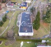 Aerial view of a building in Helcmanovce, surrounded by greenery and nearby houses.