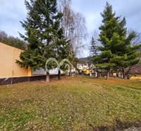 Trees near the building in Helcmanovce with a view of the hills and part of the village.