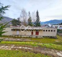 A building in Helcmanovce surrounded by nature with hills in the background.