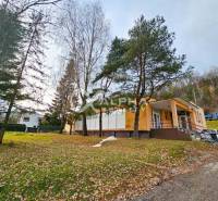 A building in Helcmanovce surrounded by trees, with a staircase leading to the entrance.