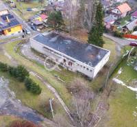 A building in Helcmanovce surrounded by greenery and other houses in a snowy landscape.