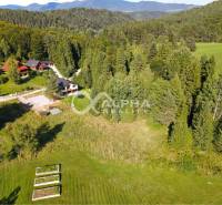 Meadow plots for housing in Spišské Vlachy surrounded by forests and cottages.