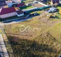 Lands in Spišské Tomášovce for housing, surrounding houses, construction equipment, grassy area.