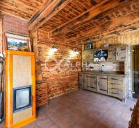 Wooden interior with a tiled stove and kitchen unit in a family house.