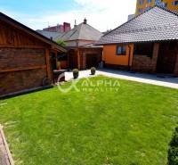 Garden and buildings of a family house in Spišská Nová Ves with a lawn and paving.