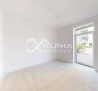 An empty room in a 3-bedroom apartment with a view of the terrace.