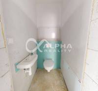 A cozy bathroom with a toilet and a sink in a 3-room apartment with unpainted walls.
