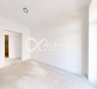 Spacious room in a 3-bedroom apartment with white walls and a large window.