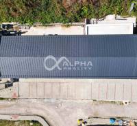 A view from above of a long building with a roof, parking, and surrounding greenery in Spišská Nová Ves.