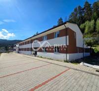 An apartment building in Spišská Nová Ves surrounded by greenery and a paved road.