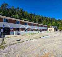 The exterior of a 3-room apartment in Spišská Nová Ves surrounded by a forest and a parking lot.
