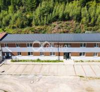 A building in Spišská Nová Ves with a parking lot, surrounded by a green forest.