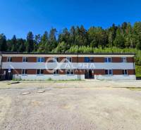 A building in Spišská Nová Ves near the forest, part of a 3-room apartment, parking lot in the foreground.