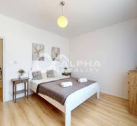 Bedroom in a 2-room apartment with a bed, wooden floor decor, and furniture.