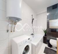 Bathroom of a 2-room apartment with a toilet, washing machine, and bathtub, ceramic tiles.