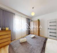 Bedroom in a 2-room apartment with wood-patterned flooring, furniture, and decorations.