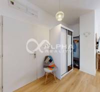 A hallway with a wardrobe, a chair, a pendant light, and a floor with a wooden decor in a 2-room apartment.