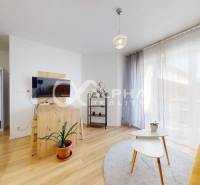 A living room in a two-room apartment with a wooden decor floor, a yellow sofa, and curtains.