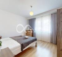 A bright bedroom with wood-decor flooring in a two-room apartment.