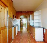 A kitchen in a 3-room apartment with a wooden decor floor and wooden wall cladding.