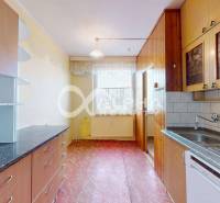 A kitchen in a 3-room apartment with wooden cabinets and a floor with a wood decor.