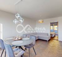 Dining area with an oval table and a sofa in a 2-room apartment, floor with wood decor.
