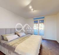 A bedroom with a bed and a wood-patterned floor in a two-room apartment.
