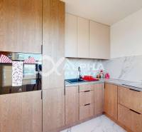 A kitchen in a 2-room apartment with a wooden decor floor and marble tiles.