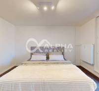 Bedroom in a 2-room apartment with a bed, white paint, and large windows.