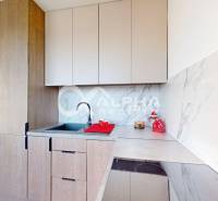 A kitchen with a marble wall and cabinets with a wood decor in a 2-room apartment.