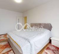 Bedroom in a two-room apartment with wood-patterned flooring and simple furnishings.