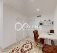 Dining room in a 2-room apartment with a beige carpet, brown chairs, and white walls.