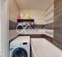 A bathroom with a washing machine and a bathtub in a 2-room apartment, tiles in toned colors.