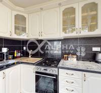 A kitchen in a 2-room apartment with white cabinets and black tiles.