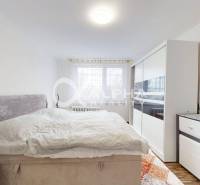 Bedroom in a 2-room apartment with a bed, wardrobe, and floor with wooden decor.