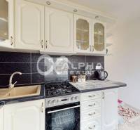 A kitchen unit with black tiles and cream cabinets in a 2-room apartment.