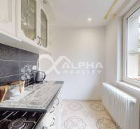 A kitchen in a 2-room apartment with black tiles and a large window.