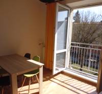 Open balcony in a one-room apartment with a wooden table and chairs.