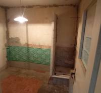 Unsuitable bathroom in a family house with exposed pipes and an older shower enclosure.