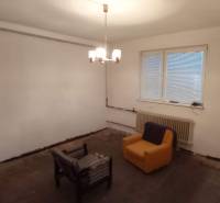 A room with a wooden floor decor, two armchairs, a window, and a radiator, family house.