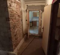 Hallway in a family house with exposed bricks and a passage to another room.