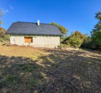 A stone structure surrounded by vegetation on agricultural and forest land in Lackov.