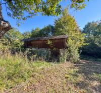 A wooden structure on agricultural and forest land in Lackov surrounded by greenery.